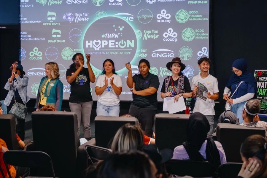 Partners applauding on stage under the #TurnHOPE:ON screen