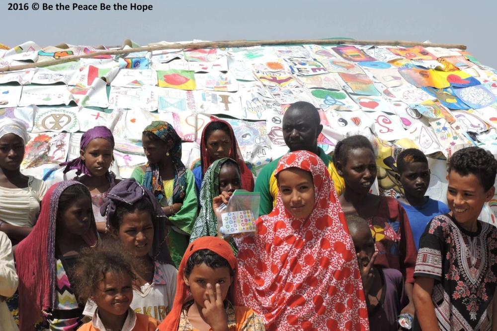 Children in Burkina Faso in front of a tent covered in paintings of hope