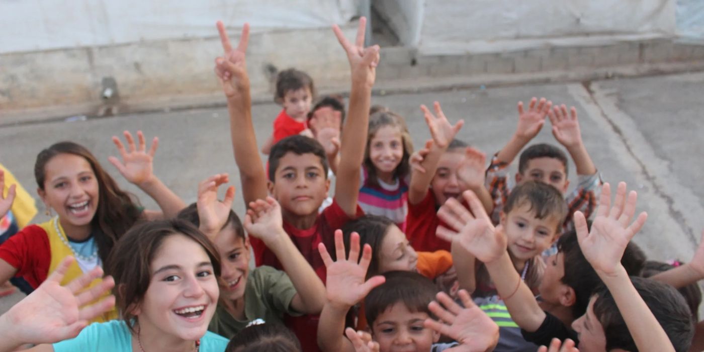 Smiling children in the Darkar refugee camp raising their hands