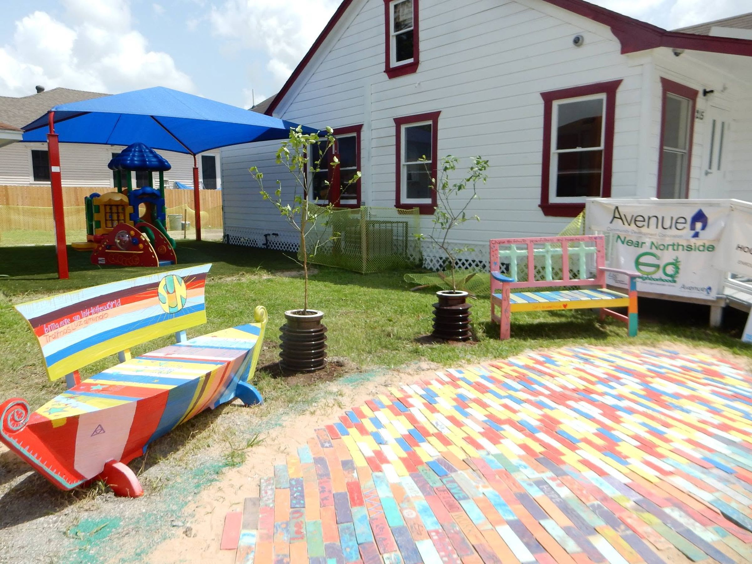 A colorful outdoor gathering space with a painted bench, a painted boat and a rainbow brick path, made by students