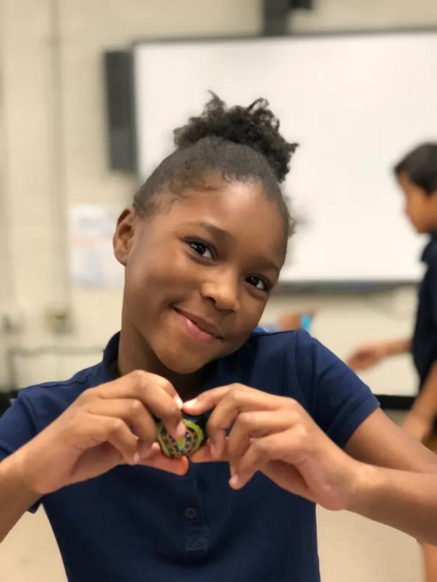 A smiling student holding a small handmade heart