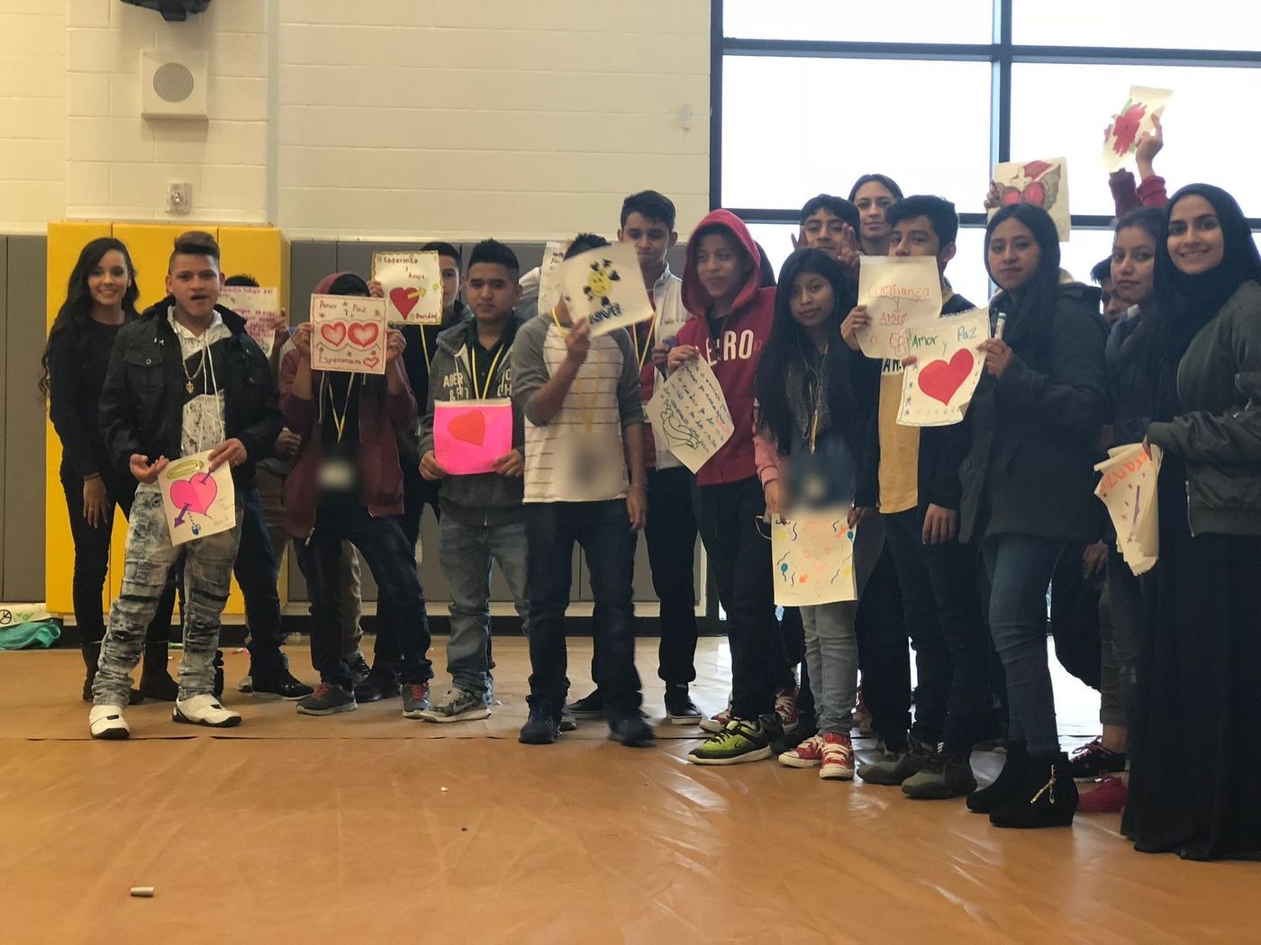 Young people holding up the hearts and messages they drew