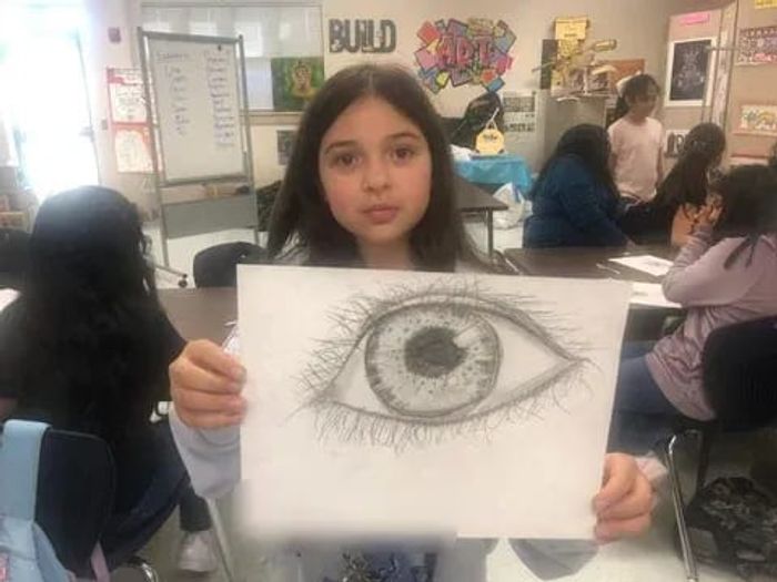 A student holding up the detailed eye she drew