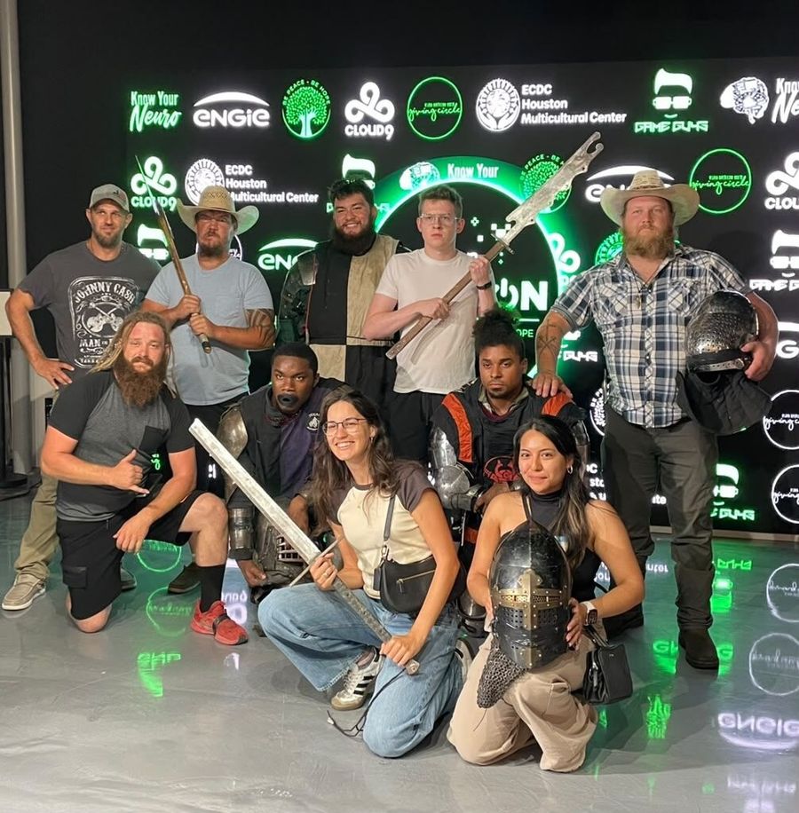 The armored fighters and their team pose with swords and helmets