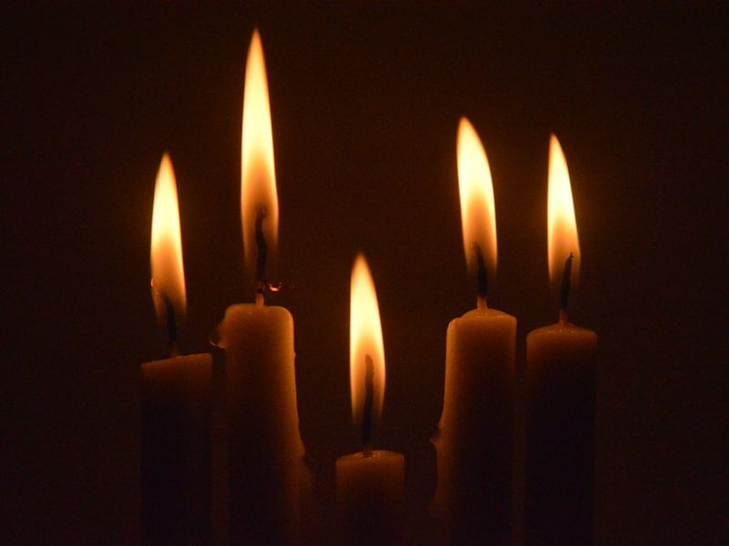 A row of candles burning in a dark room