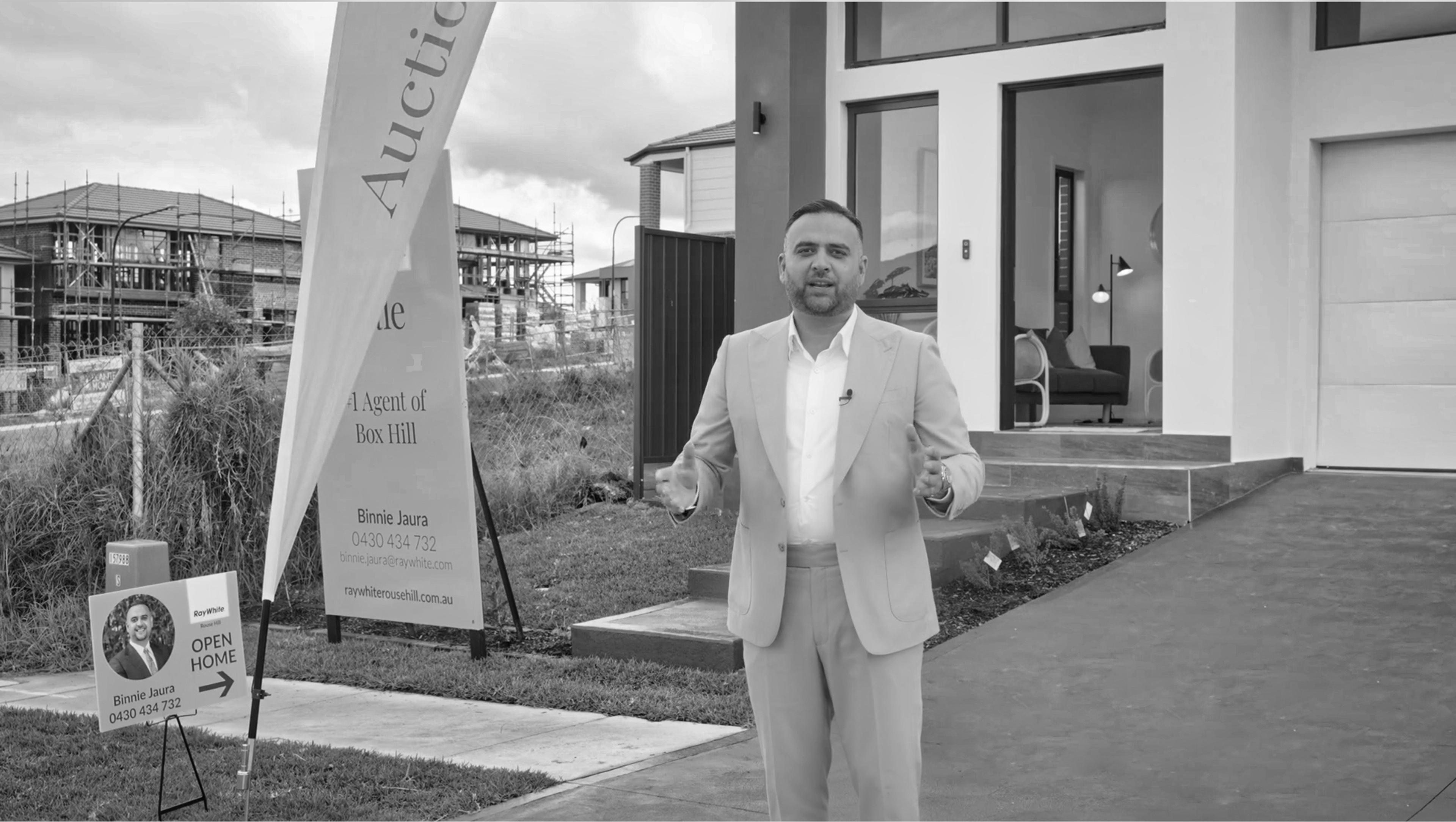 Binnie Jaura, real estate agent in front of property at an auction event.