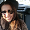 a woman wearing sunglasses and a scarf smiles for the camera