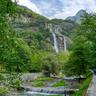 a waterfall is surrounded by trees and mountains