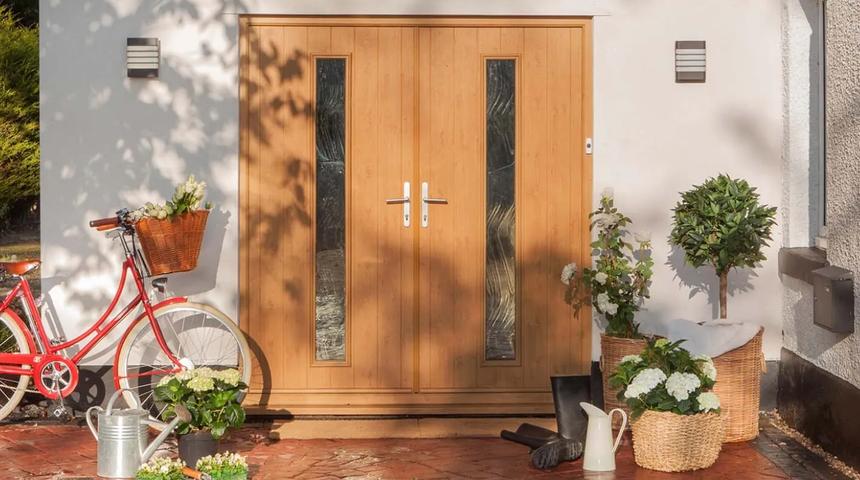 Light wood double doors with narrow glazed panels, on a tiled porch