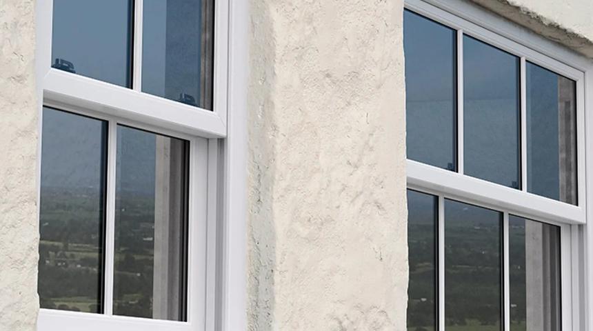 White windows set into a rendered wall, looking over open country