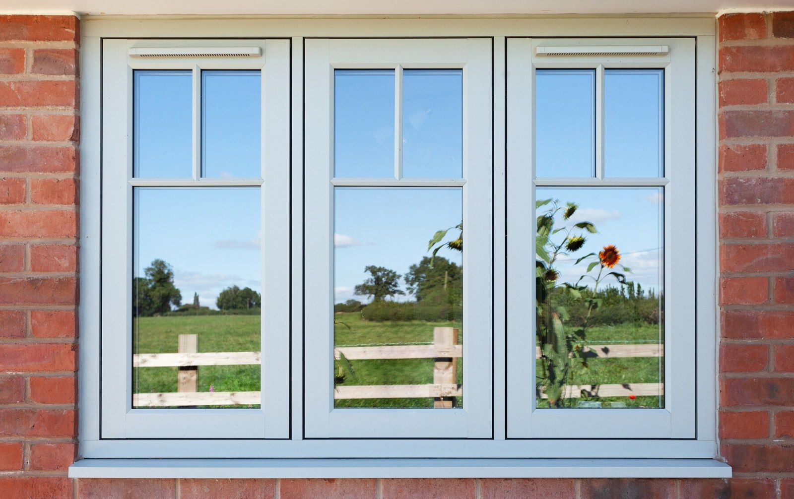 Pale grey Residence 7 flush casement windows with glazing bars in a red-brick wall