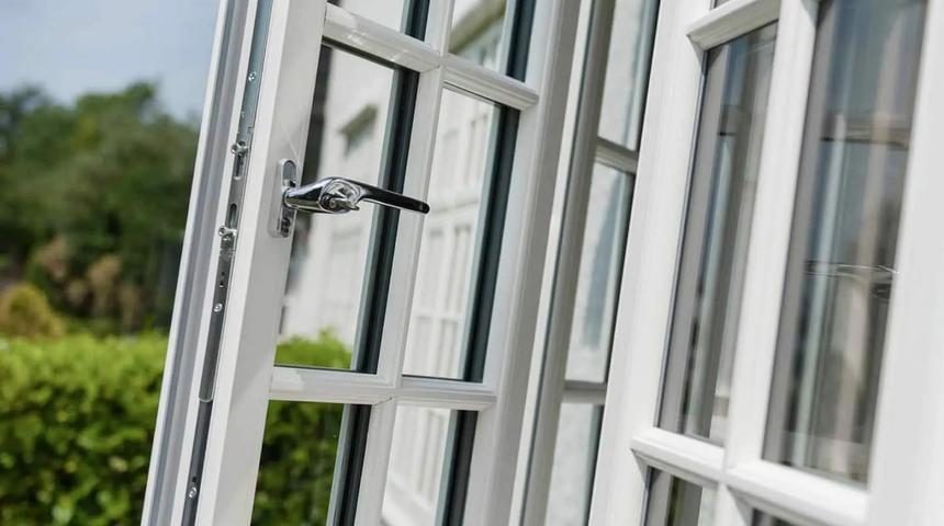 White casement window open on its side, with glazing bars and a metal handle