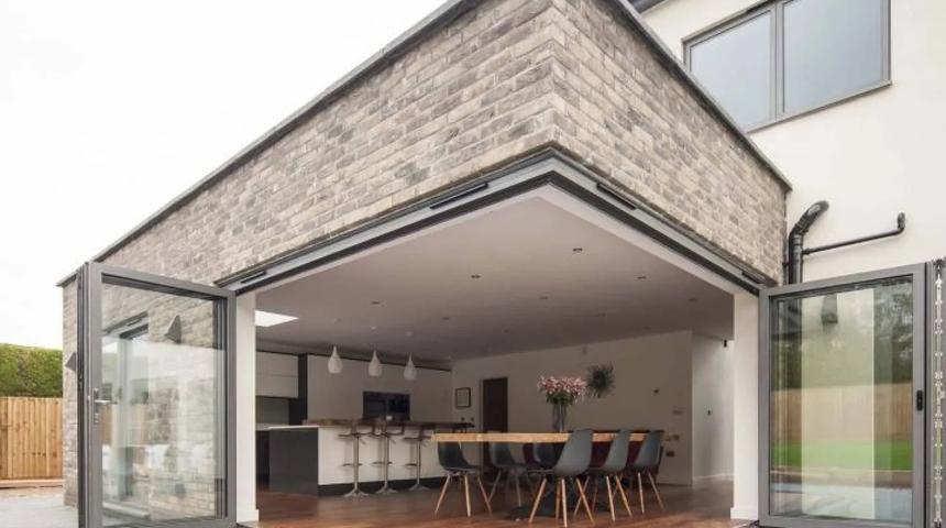 Corner bifold doors folded open on a brick extension, with a dining table inside