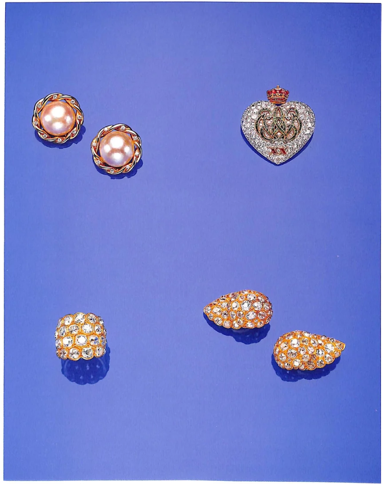 A group of lots from the 1987 Sotheby's sale catalogue: pearl and diamond earclips, a diamond and enamel coronet brooch, a pavé diamond ring, and coral and diamond shell-shaped earclips.