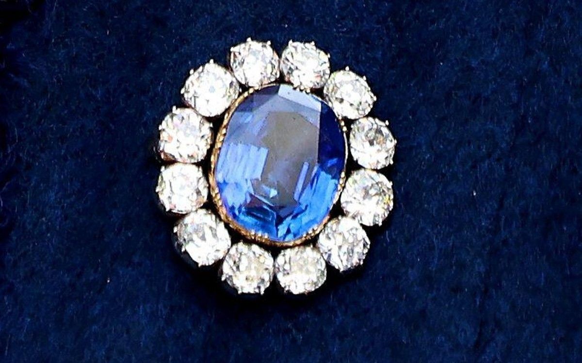 Prince Albert's Sapphire Brooch, an oval blue sapphire surrounded by a ring of diamonds set in gold.