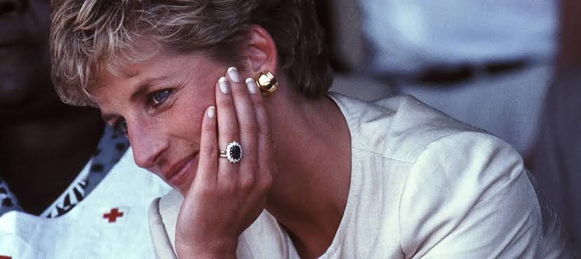 Princess Diana wearing her sapphire and diamond engagement ring, resting her hand against her face.