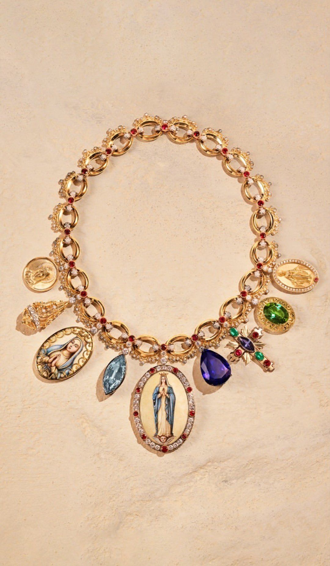 A Dolce & Gabbana gold charm necklace hung with an amethyst, a cross, coins, and enamelled Madonna miniature medallions.