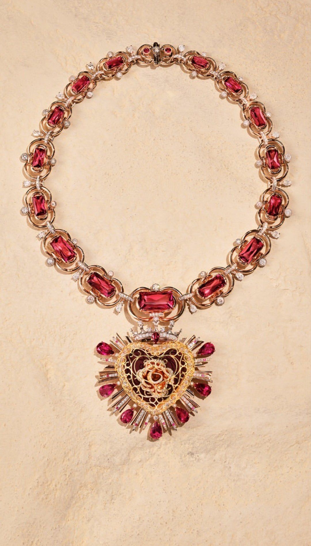 The Dolce & Gabbana Sacred Heart Parure: a rose gold and pink tourmaline collar necklace with a gold filigree Sacred Heart pendant set with rubies and diamonds.