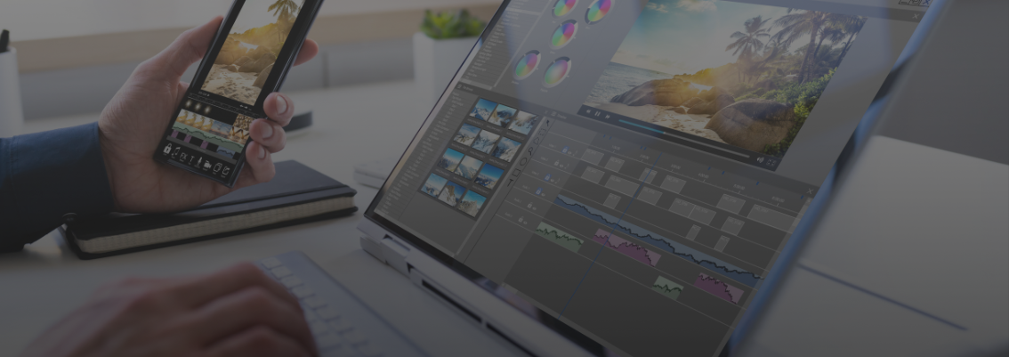 A person's hands are visible, one holding a smartphone displaying an image editing interface with a beach photo, and the other typing on a laptop. The laptop screen shows a video editing software interface with a timeline and a preview of a tropical beach scene, indicating multimedia content creation.