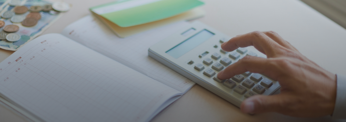 Hands operating a calculator next to an open notebook and some coins, representing the process of calculating costs or potential savings for SMM tool subscriptions.