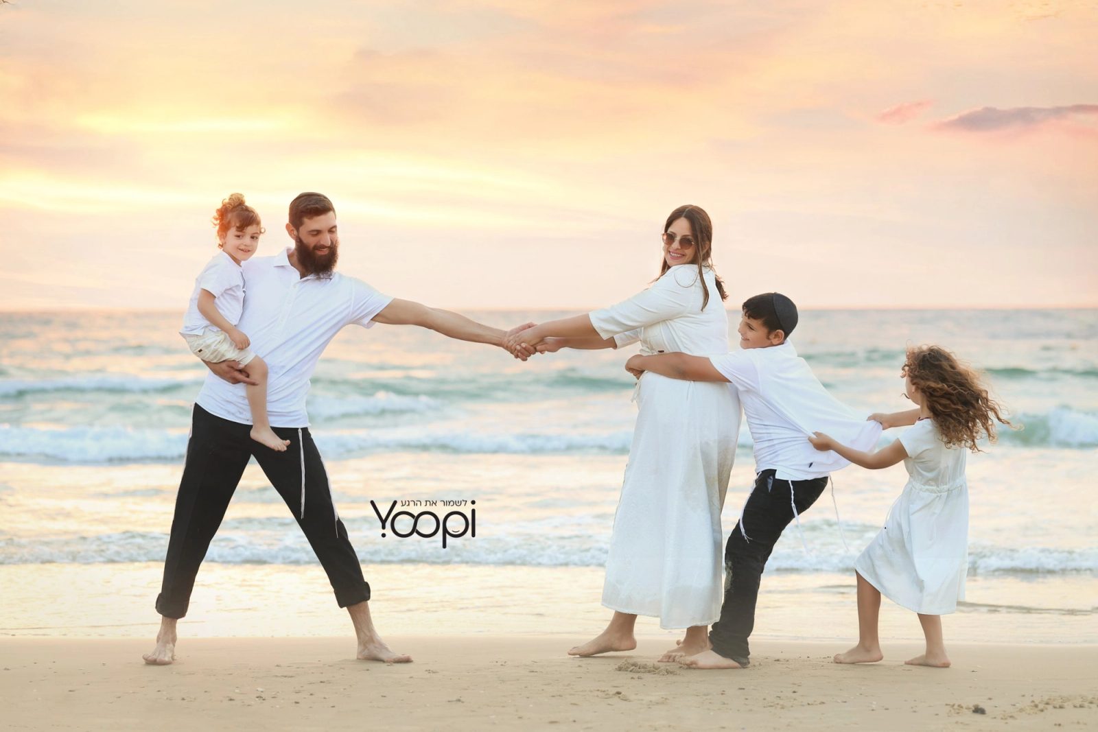 משפחה 10 - משפחה משחקת ואוחזת ידיים בחוף בשקיעה