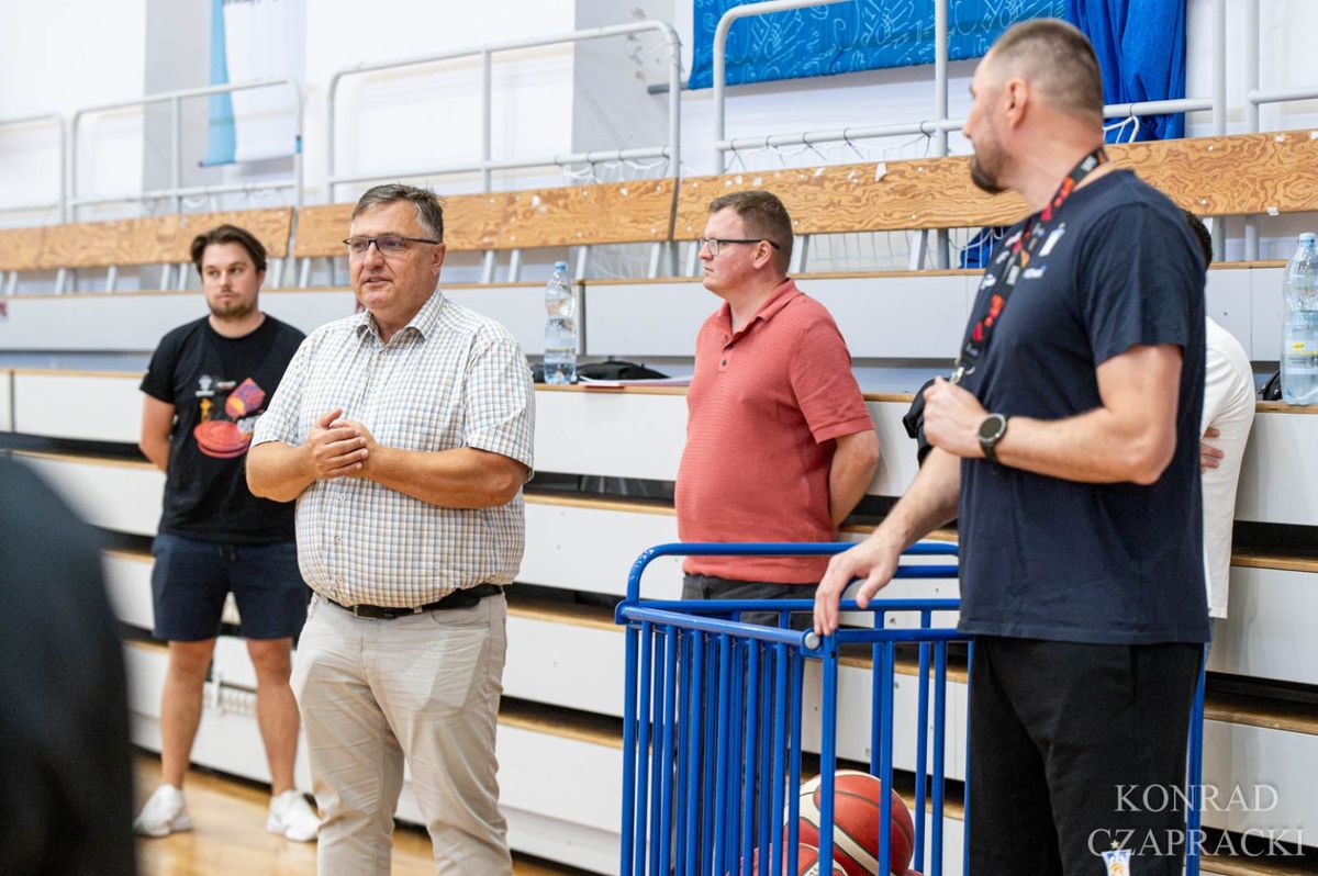 Przedstawiciele klubu rozmawiają przy linii boiska w hali podczas treningu.