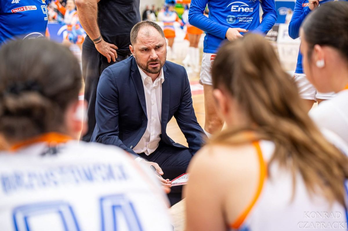 Trener Wojciech Szawarski klęczy przy zawodniczkach i udziela wskazówek w czasie przerwy na żądanie.
