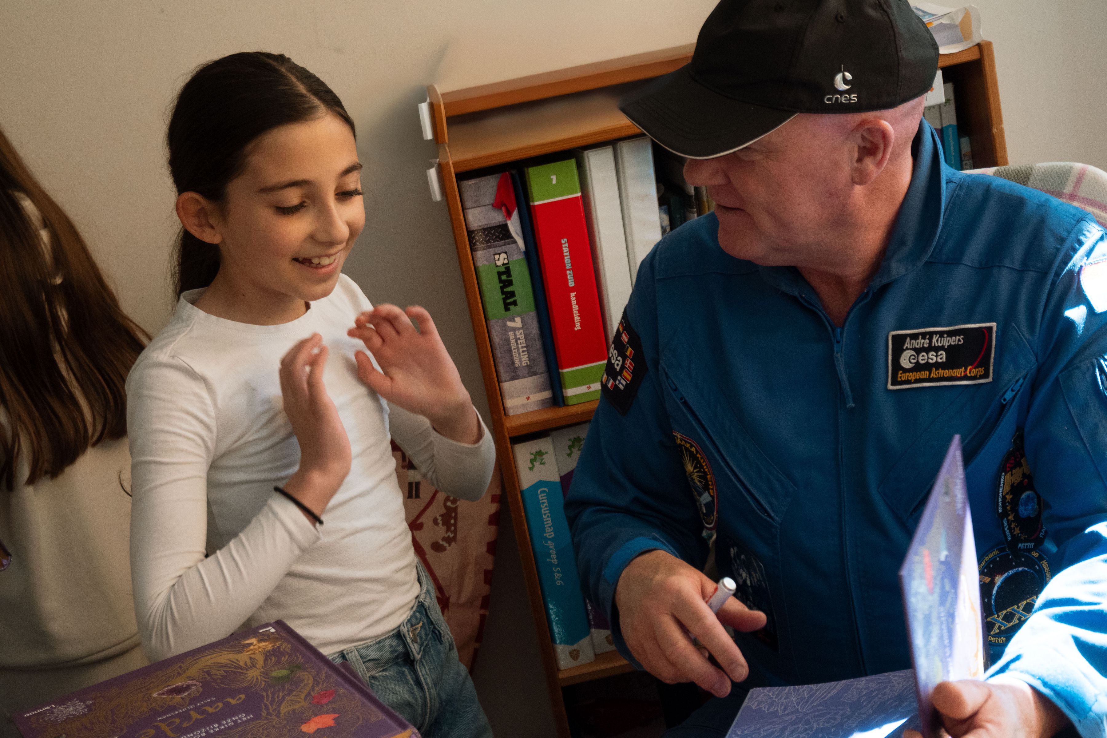 Andre Kuipers hands over a book to a girl at school 