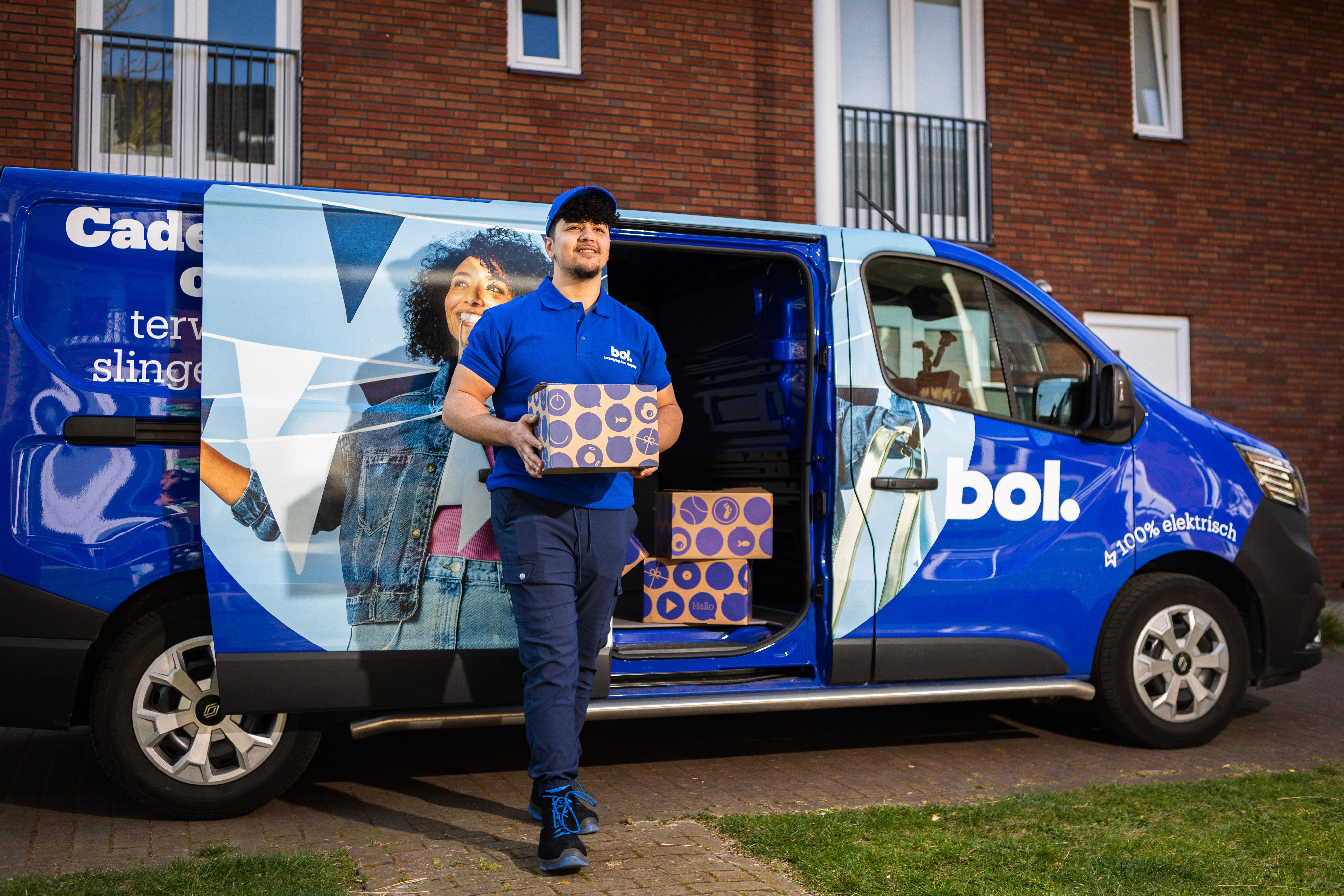 Bol chauffeur met een pakketje in zijn hand, op de achtergrond een bol-busje. 