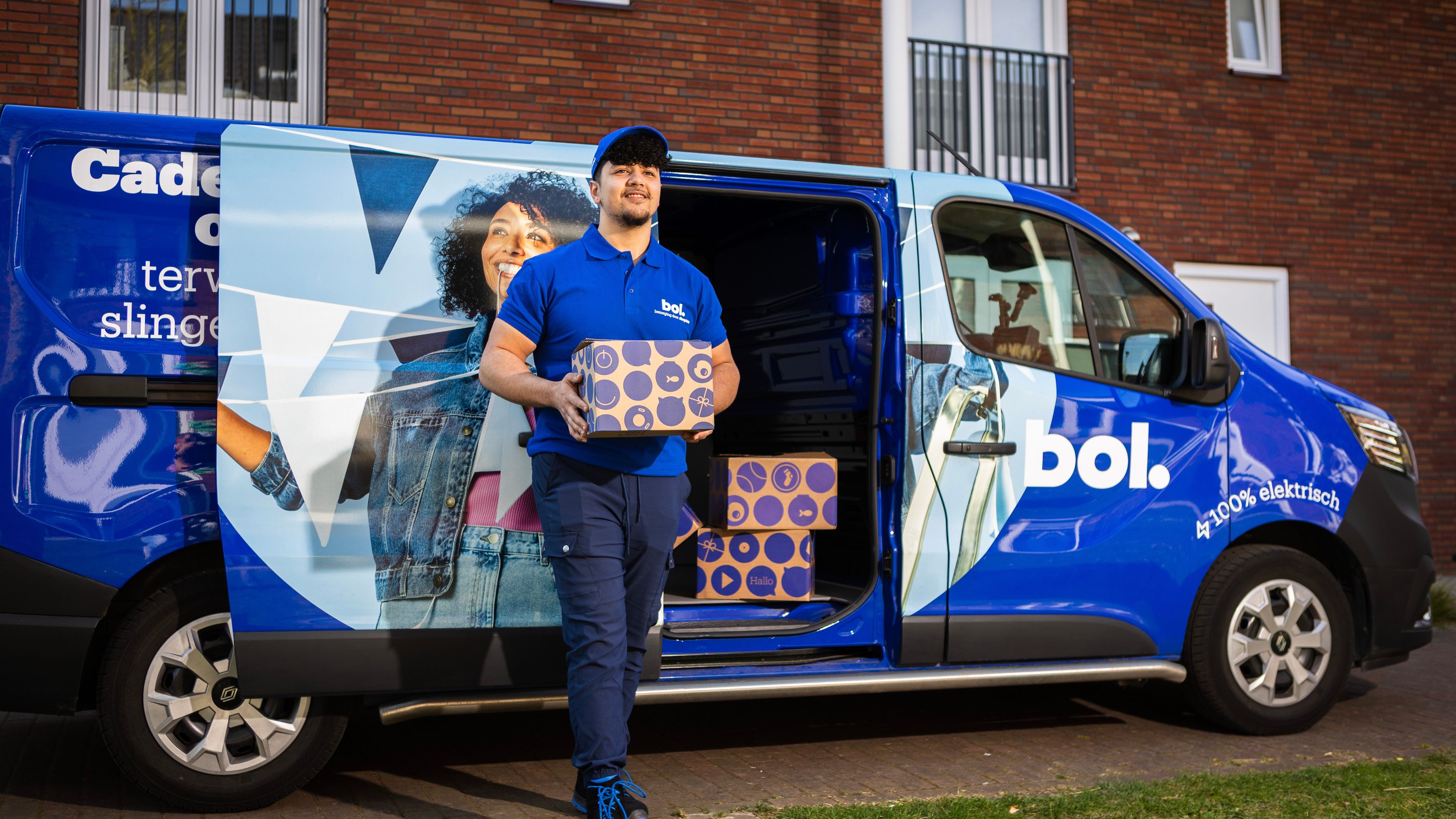 Bol chauffeur met een pakketje in zijn hand, op de achtergrond een bol-busje.