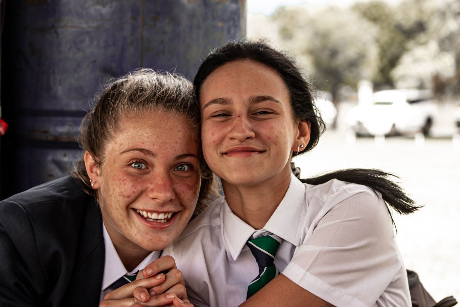 Two teenage schoolgirls hugging and laughing outdoors