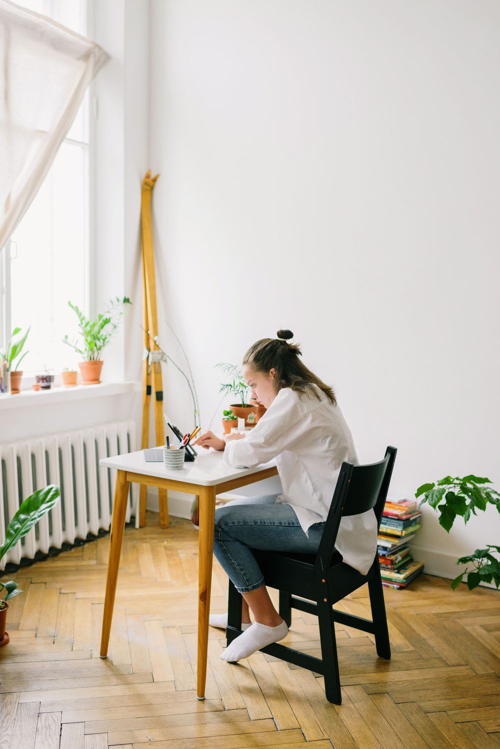 A young person working at a desk by a bright window