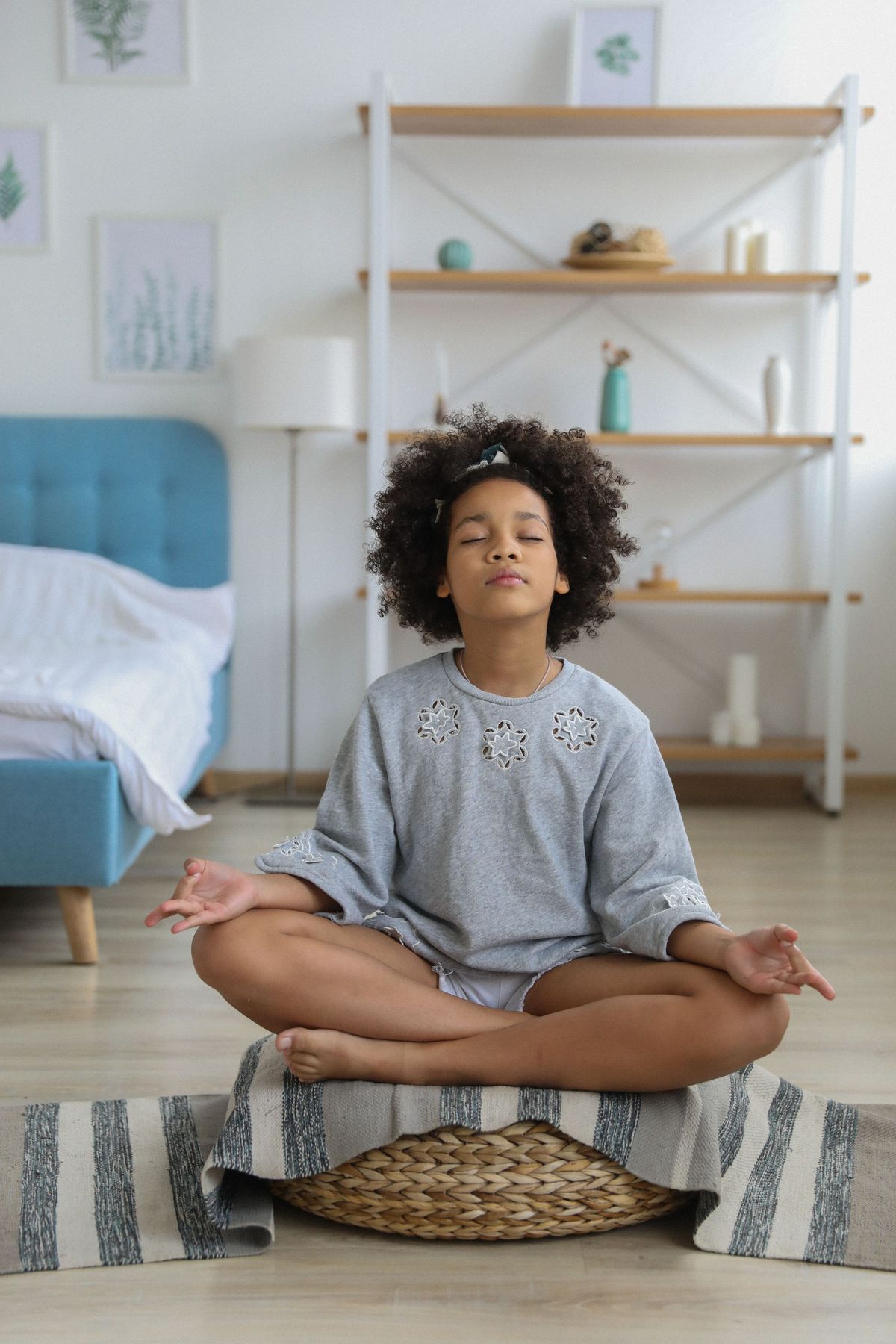 A girl meditating cross-legged in a calm, bright bedroom