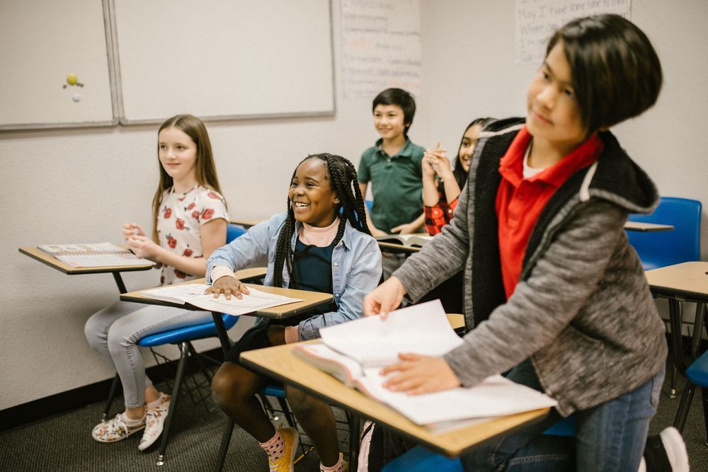 Students laughing together at their desks in a bright classroom