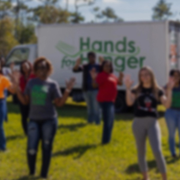 Happy people posing for a group photo in front of a charity food truck