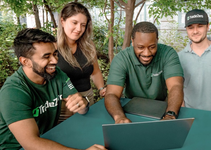 Group of friends outdoors having fun reading about a TradeZero promo from a computer screen