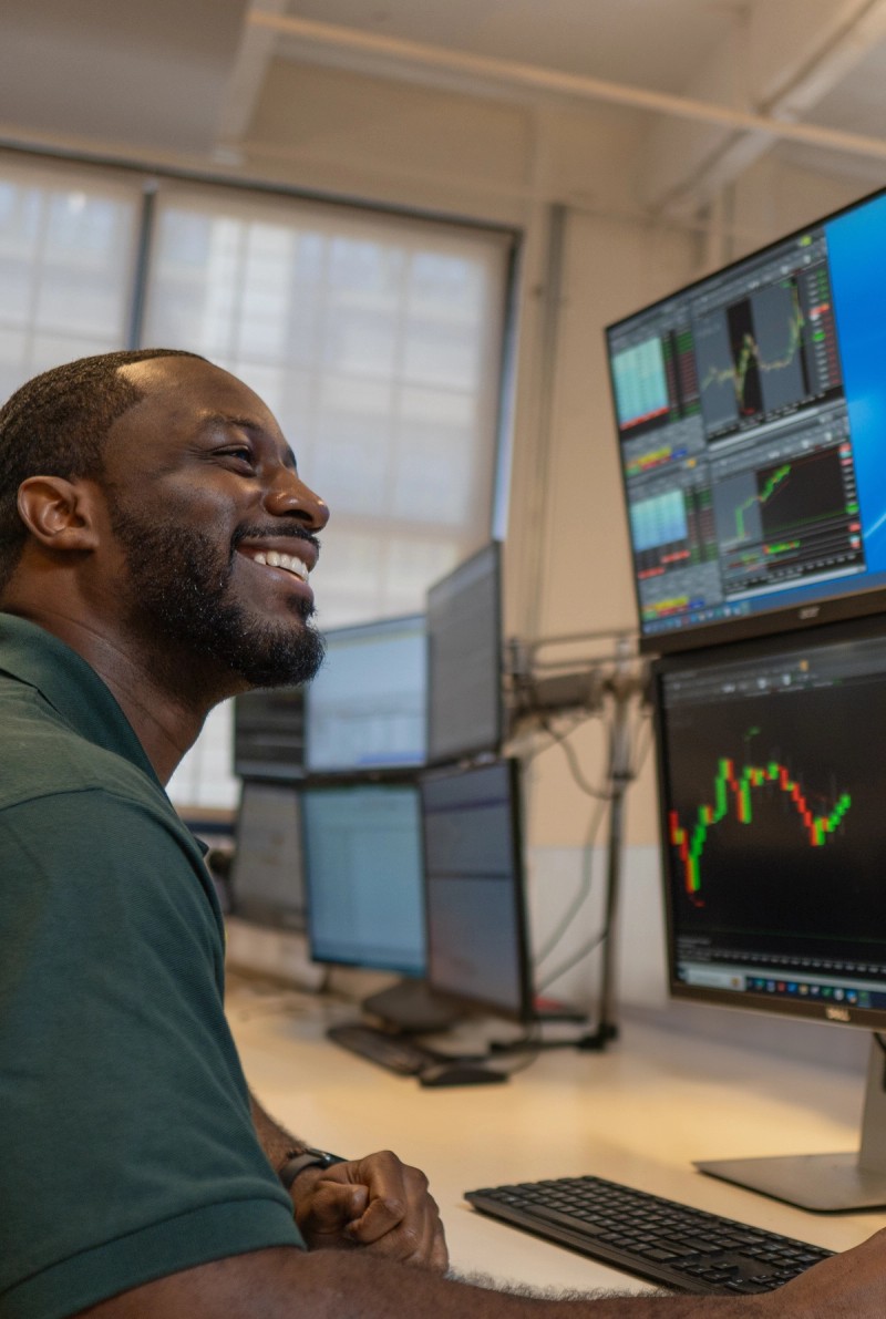 Smiling young man close to a computer showing ZeroPro trading platform