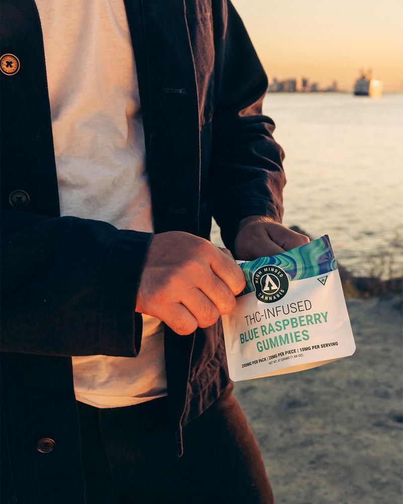 man standing riverside holding bag of gummies