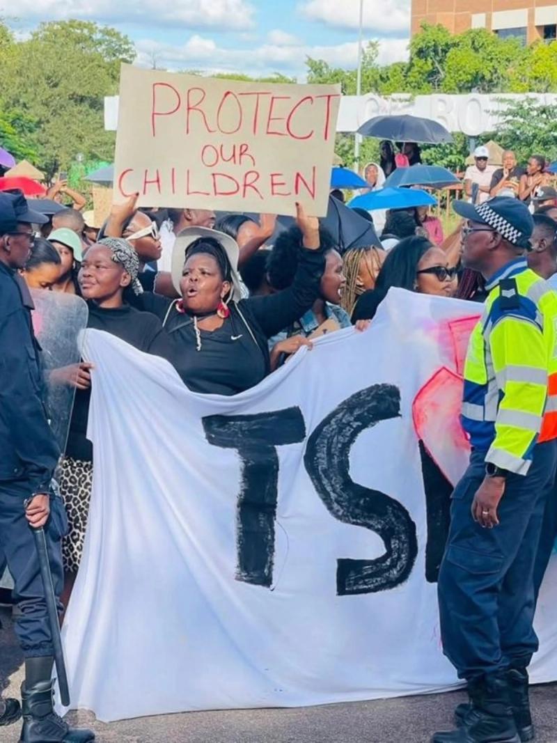 Marchers hold a 'Protect our children' sign and a banner outside Parliament.