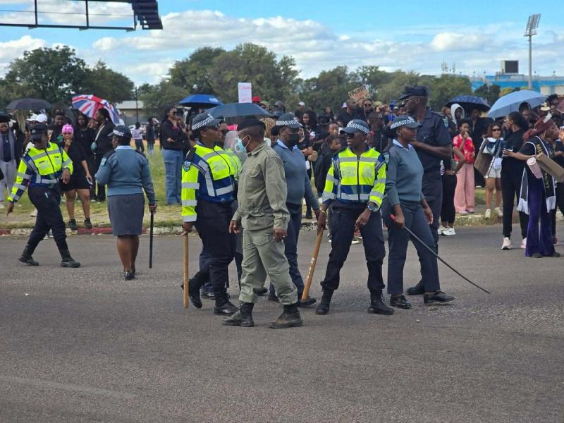 A line of police officers stands across the road from the demonstration.