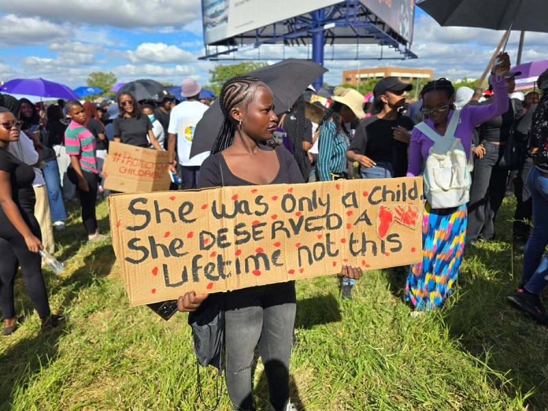 A protester holds a placard reading 'She was only a child. She deserved a lifetime, not this.'