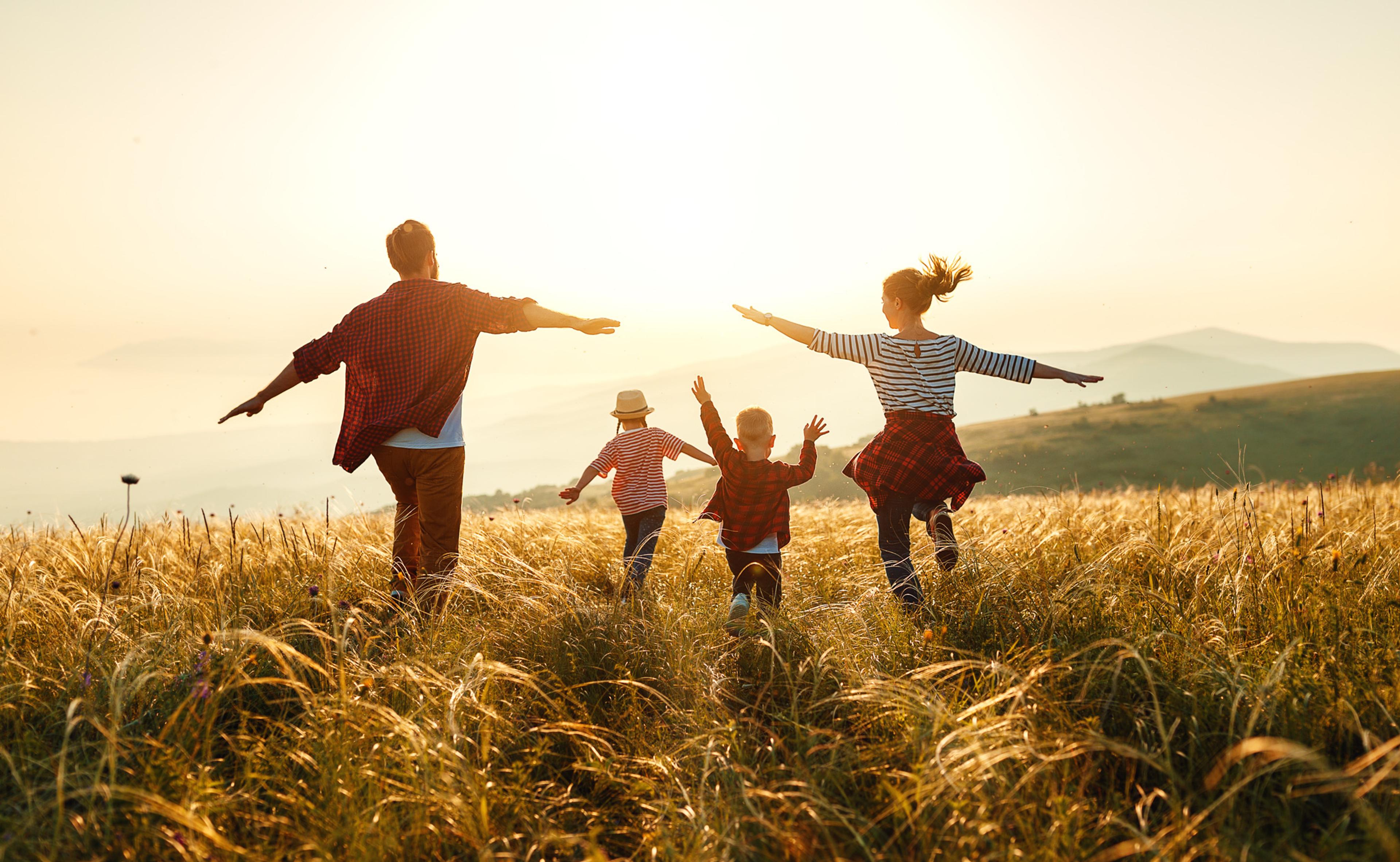 Parents and children playing in field of wheat on sunny day