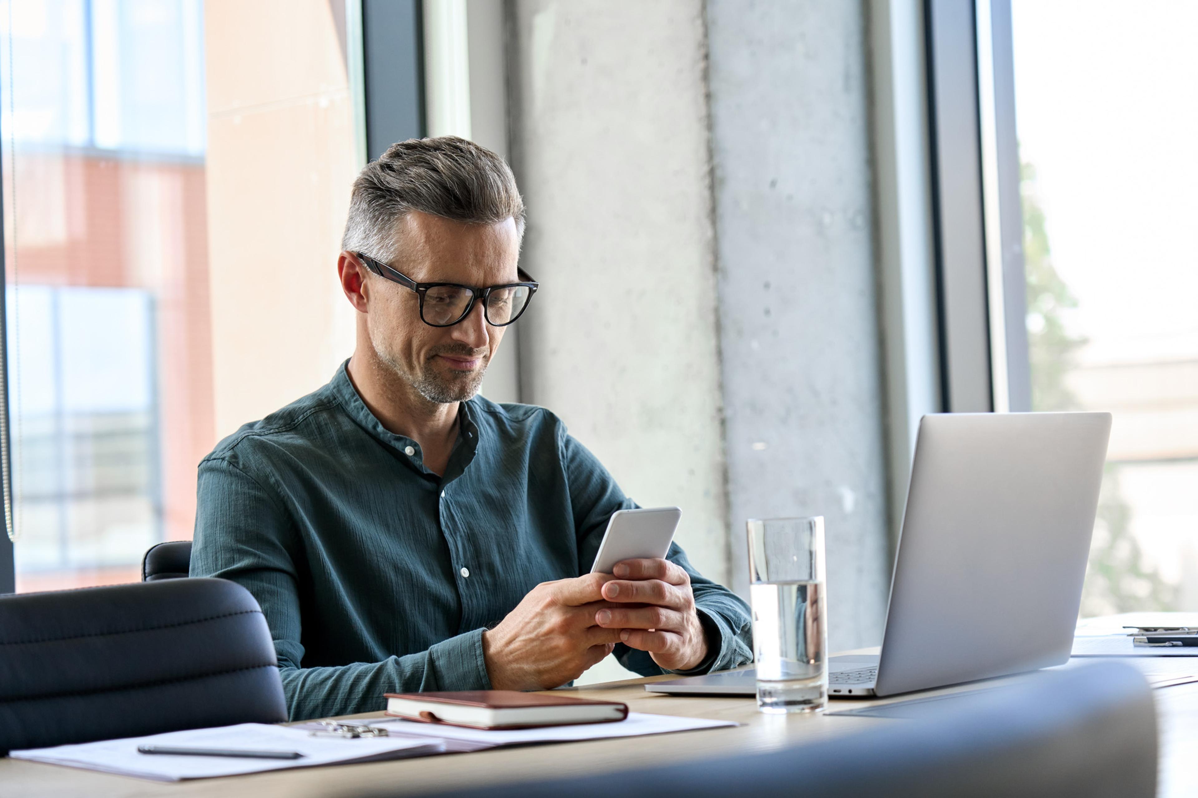 Man looking at phone reading latest updates on the screen
