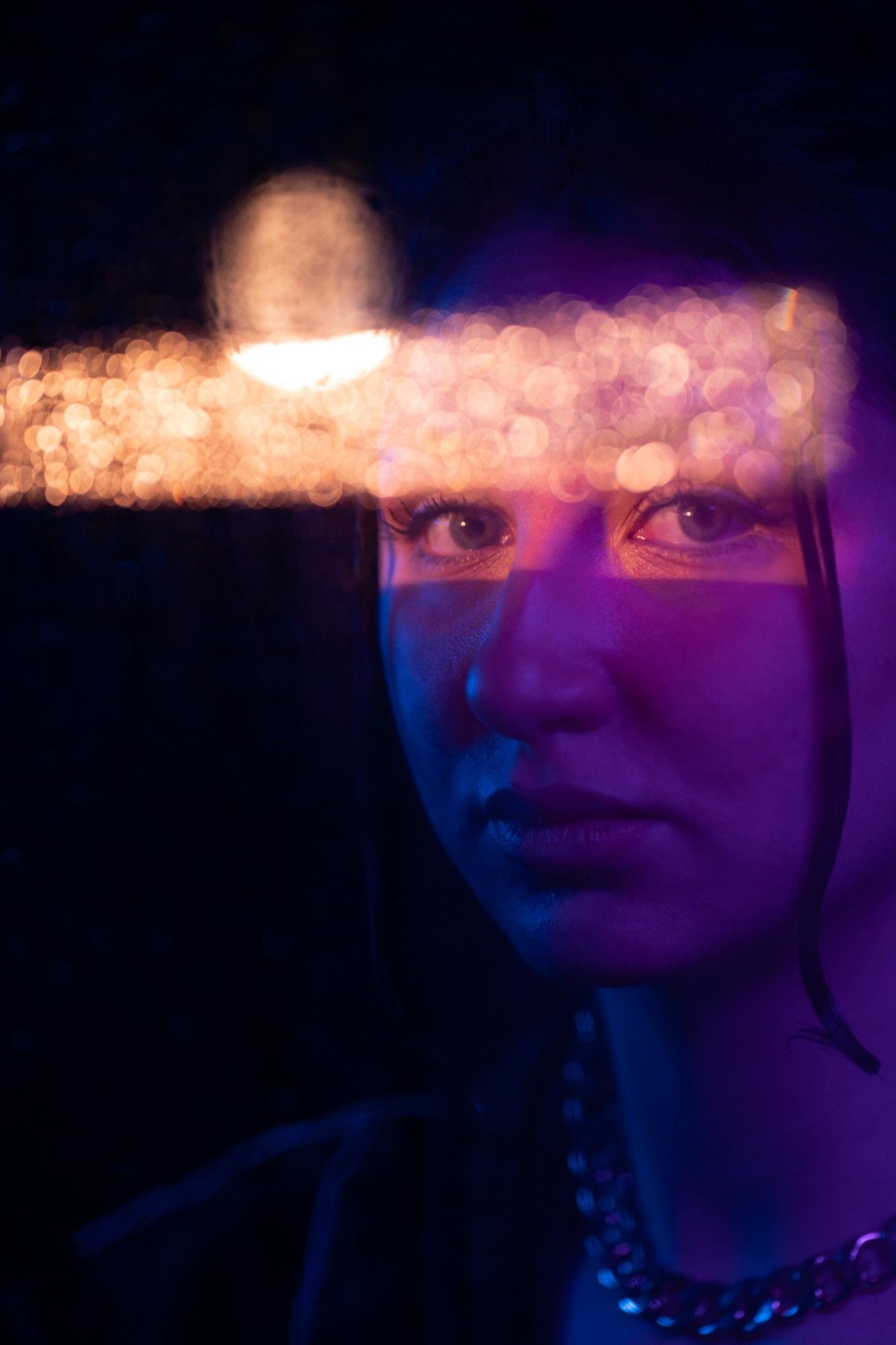 Portrait in purple light with a warm band of bokeh across the eyes