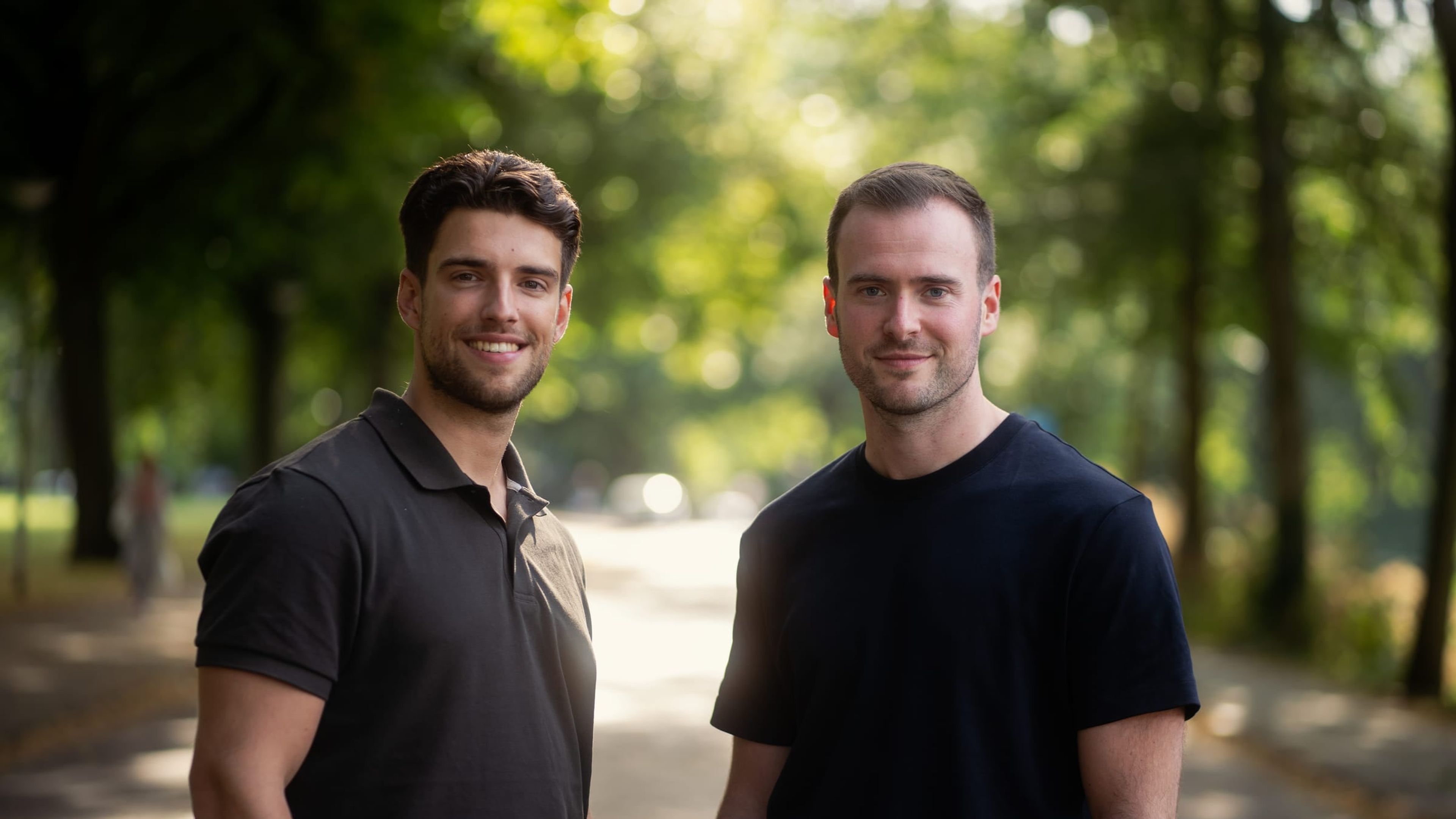 Corporate portrait of two business partners in a tree-lined avenue
