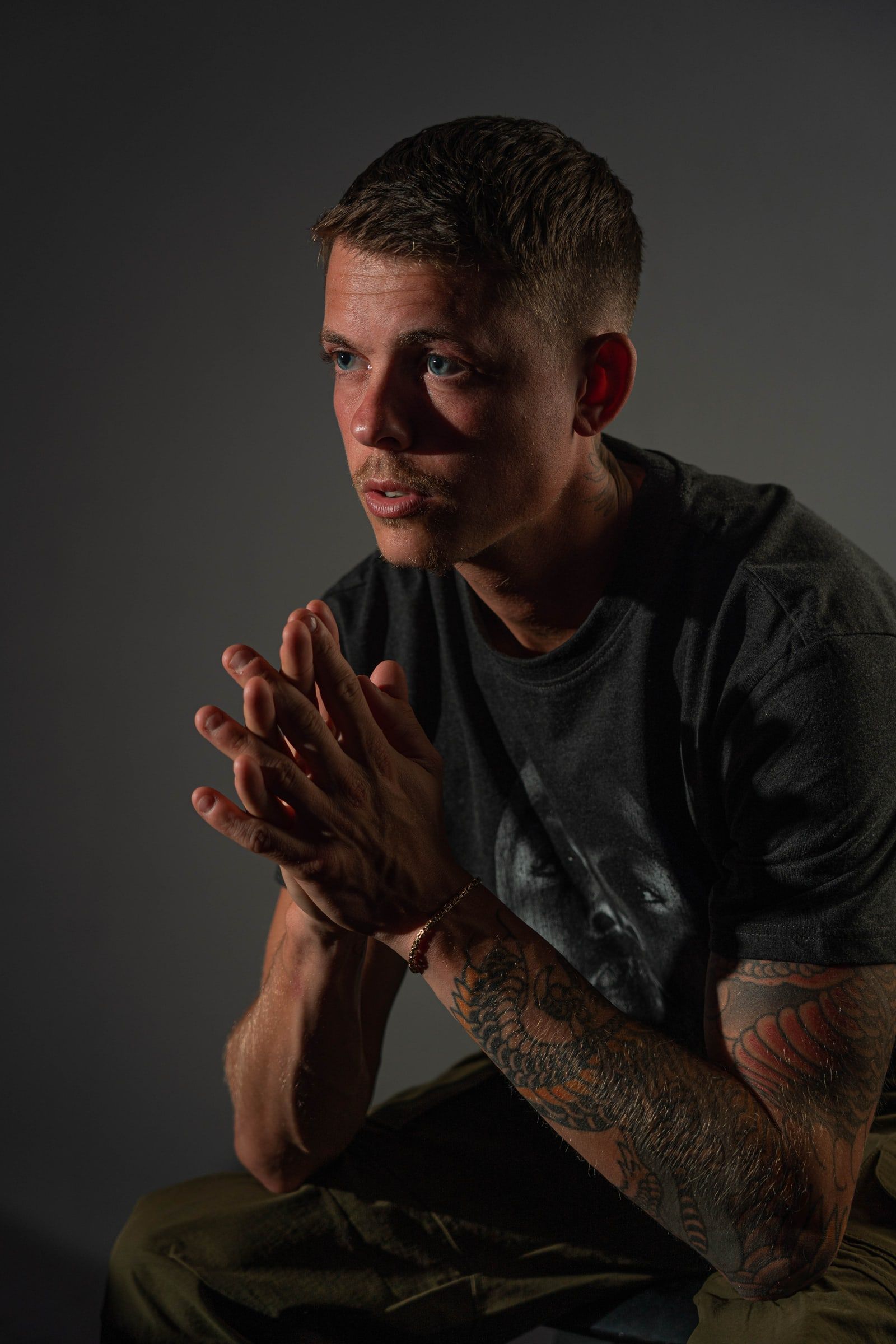 Ian with folded hands in hard side light