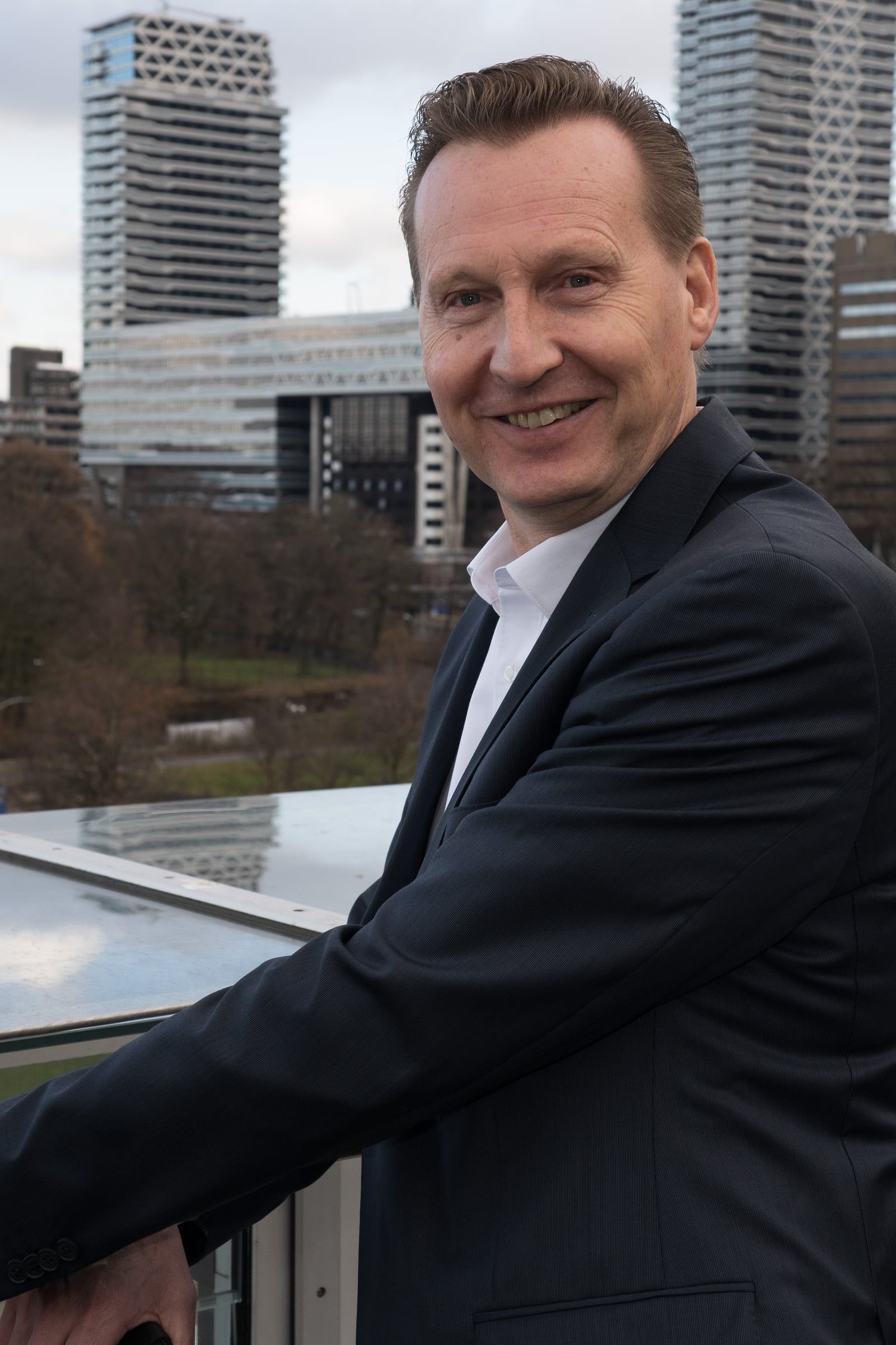 Director in a suit in front of The Hague skyline