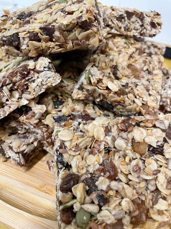 Stacked oat bars packed with raisins, dates, linseed, sunflower and pumpkin seeds on a wooden board