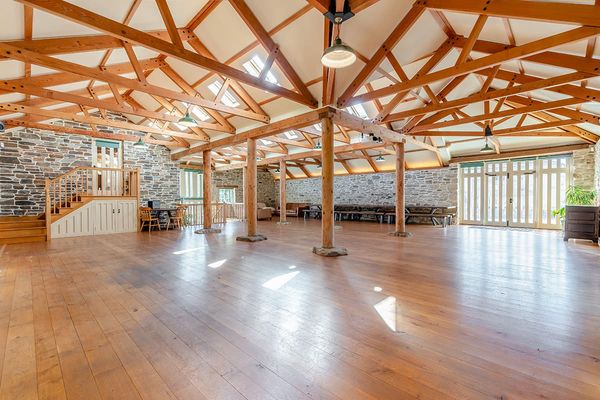 Spacious yoga shala with wooden floors, exposed timber roof beams, stone walls, skylights and glazed doors