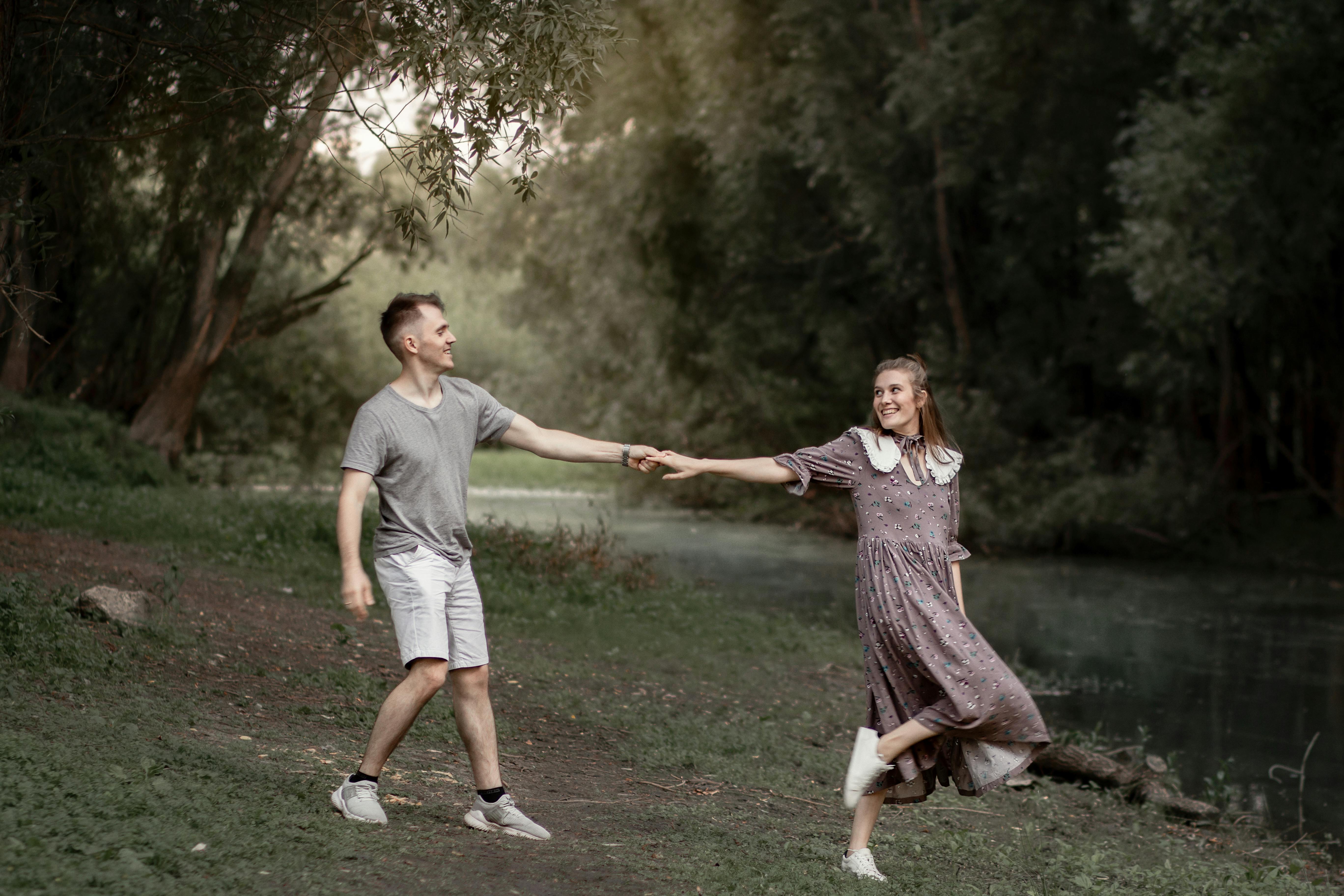 Young couple holding hands with the girl leading the boy in a nature area